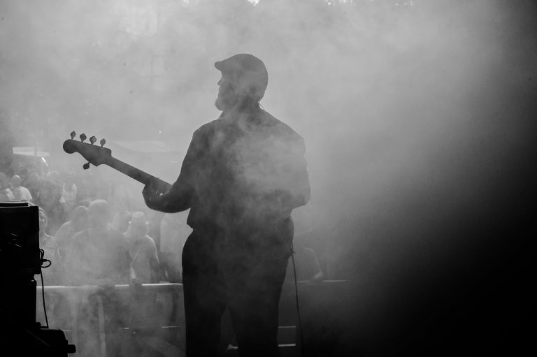 Flacher, schwarzer und weißer Musiker spielt E-Gitarre auf der Bühne mit Nebel- und Lichteffekten beim Abenteuerland Coverband.