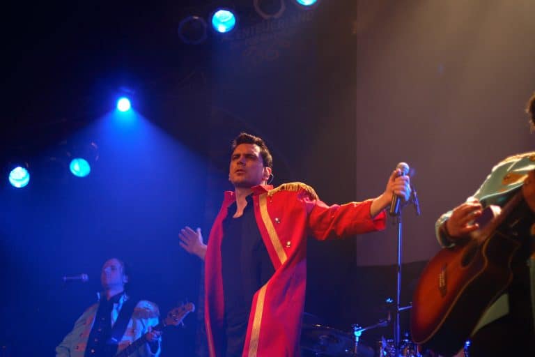 Leuchtende Bandmitglieder der Abenteuerland-Coverband während eines Live-Auftritts auf einer Bühne, mit blauen Bühnenlichtern und energiegeladener Performance, ideal für Musikliebhaber und Eventplanung.