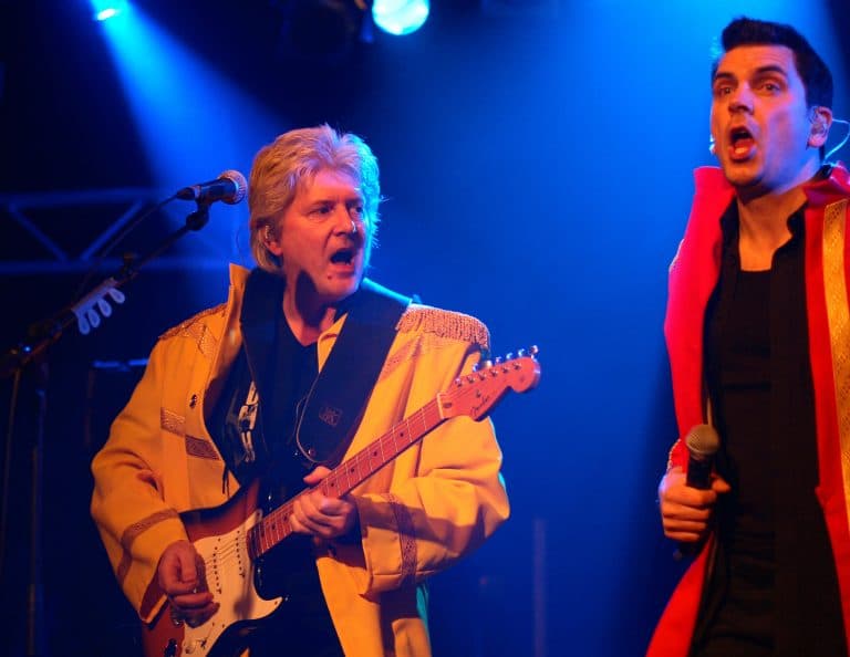 Frechen, Deutschland -Abenteuerland- Coverband bei einem Auftritt, energische Sänger und Gitarrist in bunten 70er- oder 80er-Jahre Kostümen, live Musik, Party-Event, Tanz, Spaß, Musikband, Unterhaltung, Konzert vor Publikum.