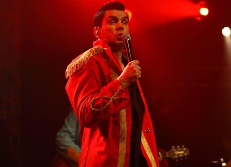 Mitreißender Partysänger der Abenteuerland Coverband bei einer Live-Performance im roten Bühnenlicht.