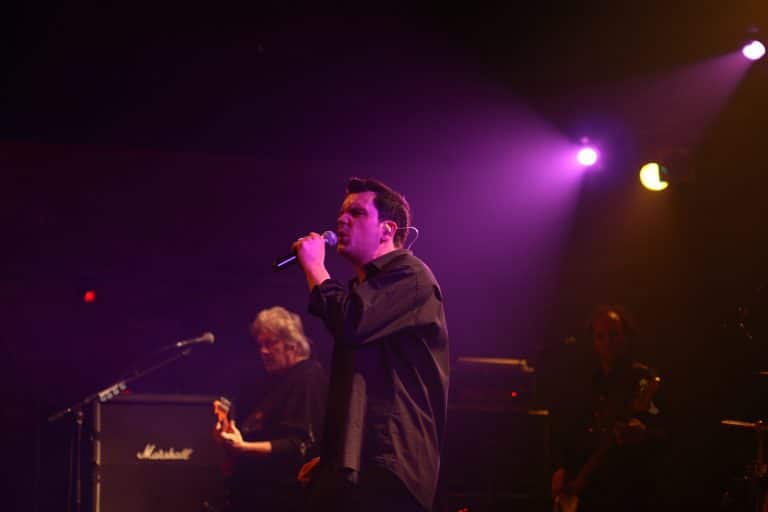 Stimmungsvolles Musik-Performance-Foto bei Abenteuerland mit Band auf Bühne, professionelle Lichtsetzung, Leidenschaftliches Singen, Musik ü24, Event, Live-Band, Musikveranstaltung, Konzert, Dekoration, stimmungsvoll.