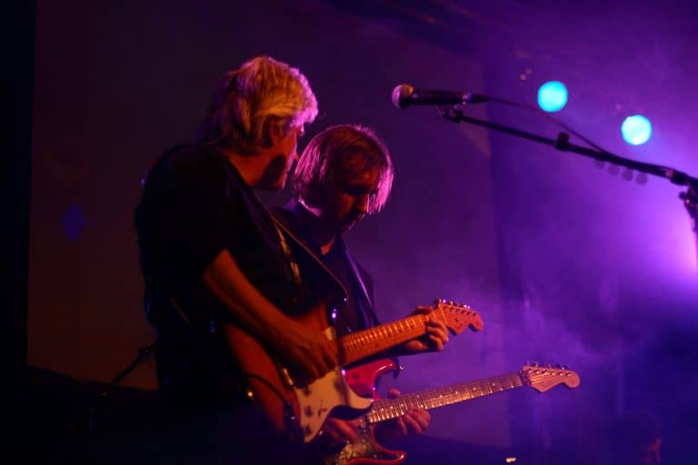 Zwei gitarristen bei abenteuerland blues rock band auf der bühne, live musik performance, stimmungvolle konzertatmosphäre, professionelle musiker, abenteuerland coverband, abenteuerland tribüne, musikveranstaltung, koncert, bandauftritt, rock- und bluesmusik, festival, publikum, lichtshow.