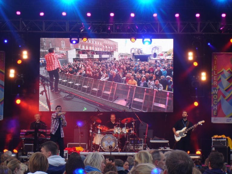 Bühne mit Live-Musik und großem LED-Bildschirm beim Abenteuerland Festival, während das Publikum die Performance genießt. Perfektes Event-Setup für eine unvergessliche Festival-Erfahrung.