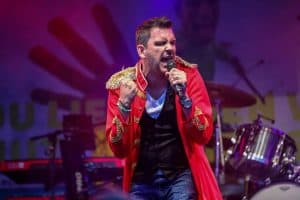 Mitglieder einer Coverband beim Live-Auftritt auf der Bühne, leidenschaftlich performing bei einem Konzert, farbenfrohe Kostüme, musikalische Darbietung, Stimmung, Unterhaltung, Festival, Band, Musik-Event, Live-Musik, Abenteuerland, Peter Maffay Cover, emotionale Performance.