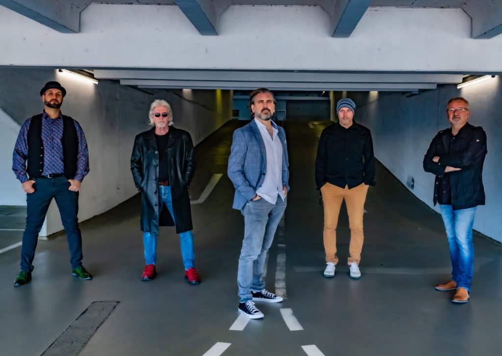 Mitglieder der Abenteuerland Coverband posieren in einer modernen, urbanen Tiefgarage, perfekt für Fans der Live-Musik und Musik-Events, mit Fokus auf Erlebnis und Musik-Entertainment.